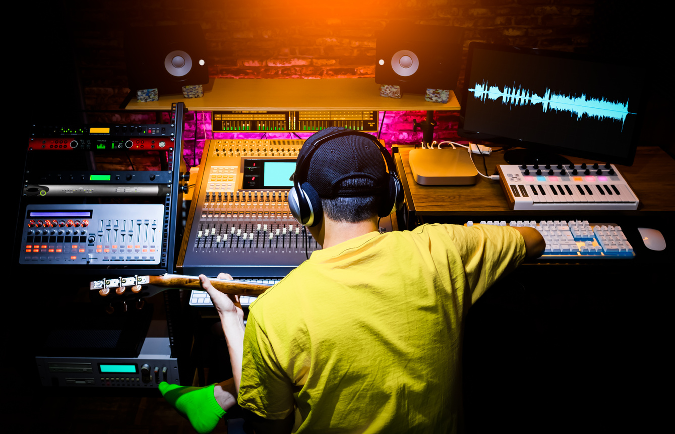 back of male asian musician recording guitar sound in home studio. music production concept